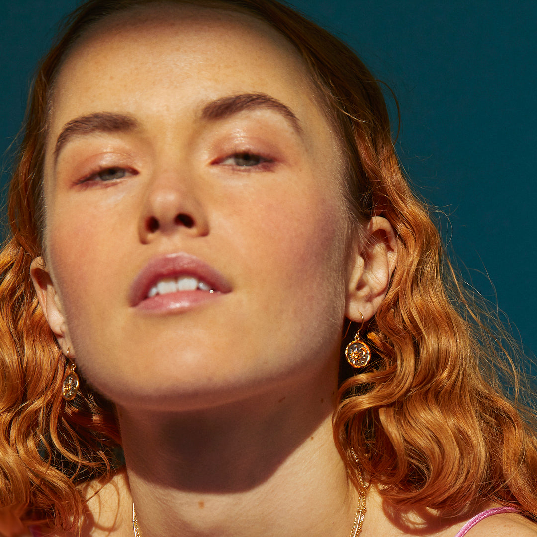  Model wearing gold and black rhodium earrings with a sun and moon design