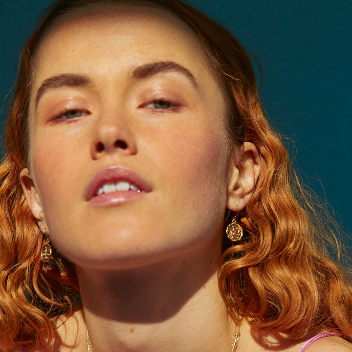  Model wearing gold and black rhodium earrings with a sun and moon design