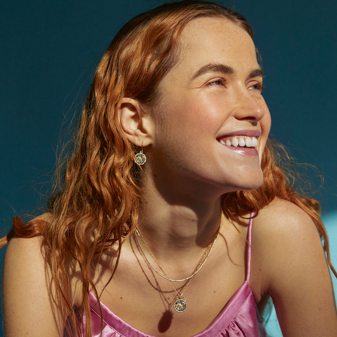 Model wearing a gold sun and moon themed necklace and earring set.