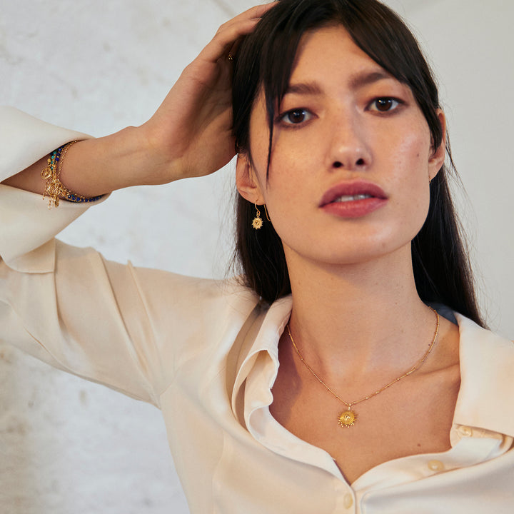 Model wearing a gold sun necklace and drop earring jewellery set with citrine gemstones