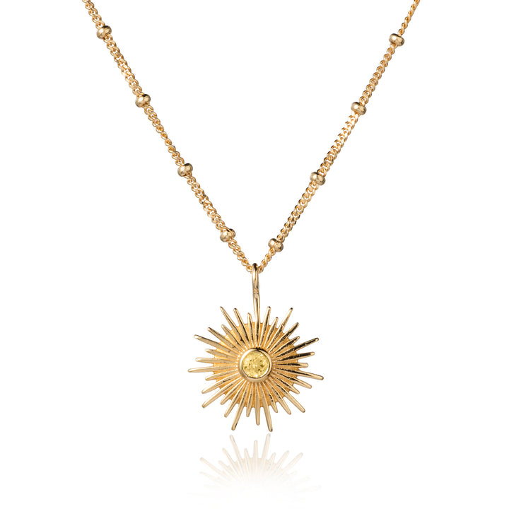 Gold sun necklace on a beaded curb chain with a citrine gemstone on a white background