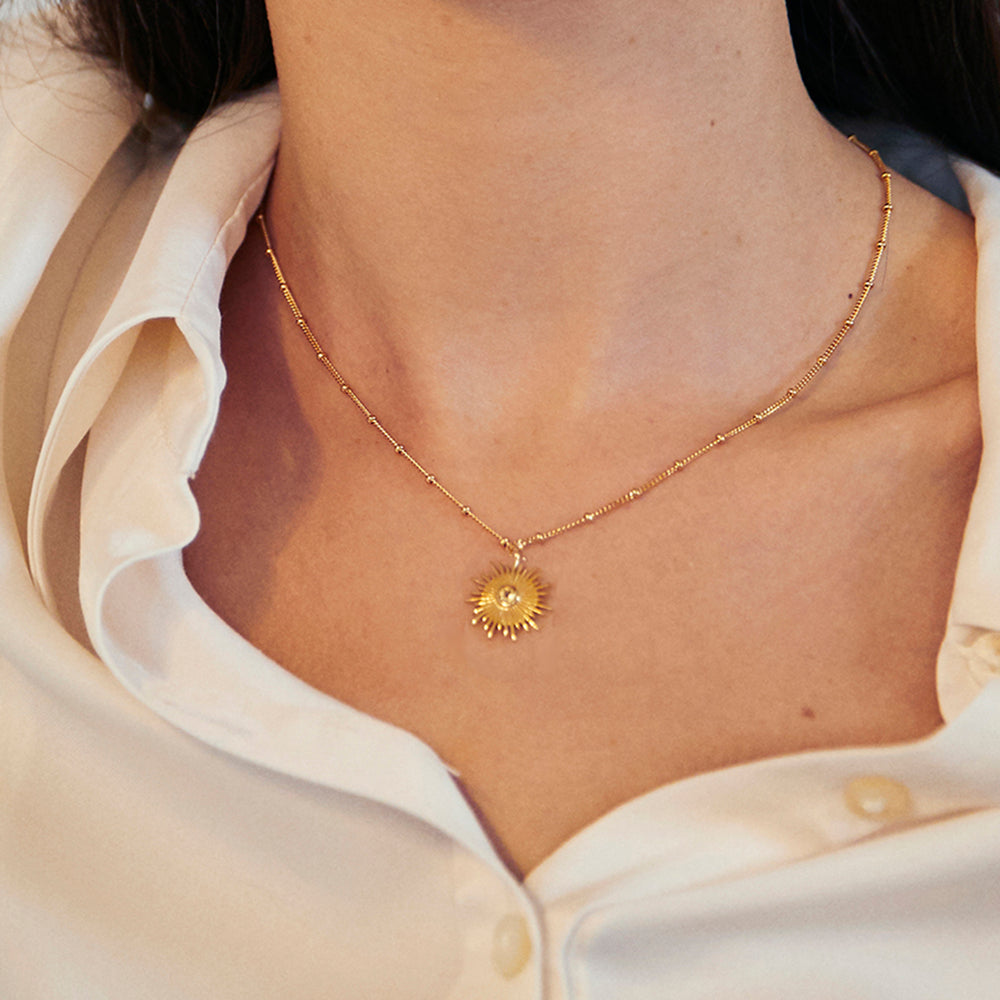 Close-up of model wearing a gold sun necklace with beaded chain set with yellow citrine