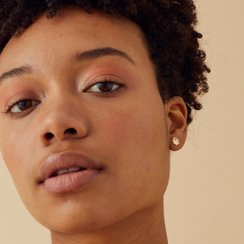 Close-up of model wearing sun post earrings in gold vermeil and white topaz