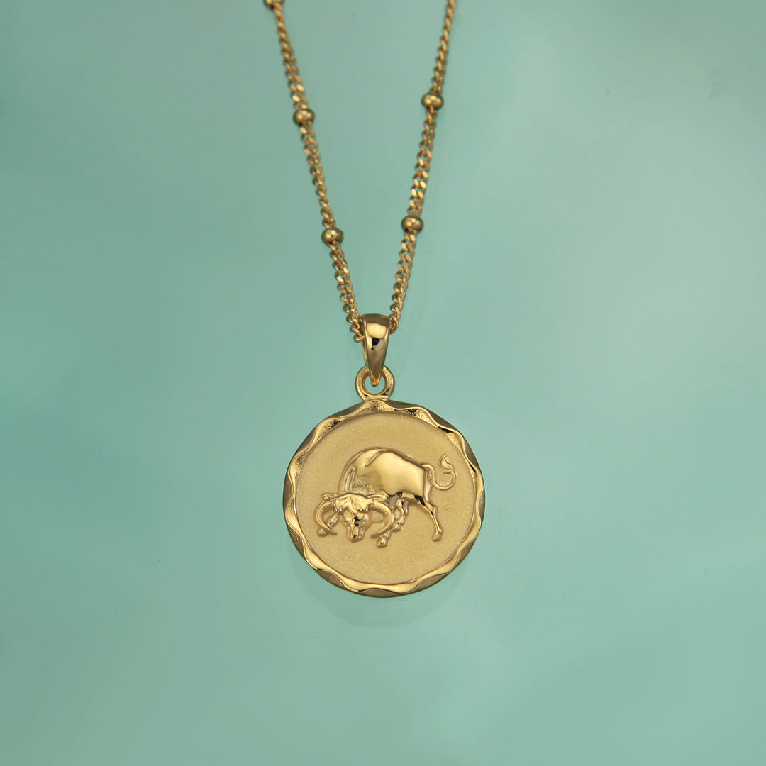 18ct gold vermeil Taurus zodiac star sign pendant necklace on a teal background
