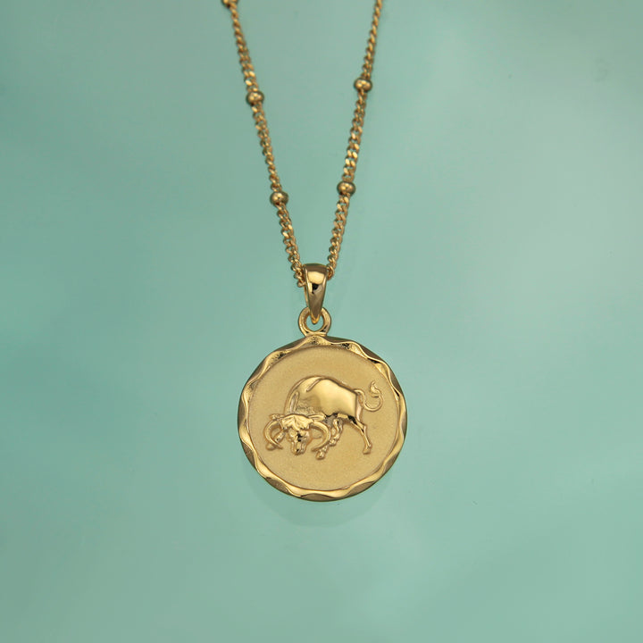 18ct gold vermeil Taurus zodiac star sign pendant necklace on a teal background