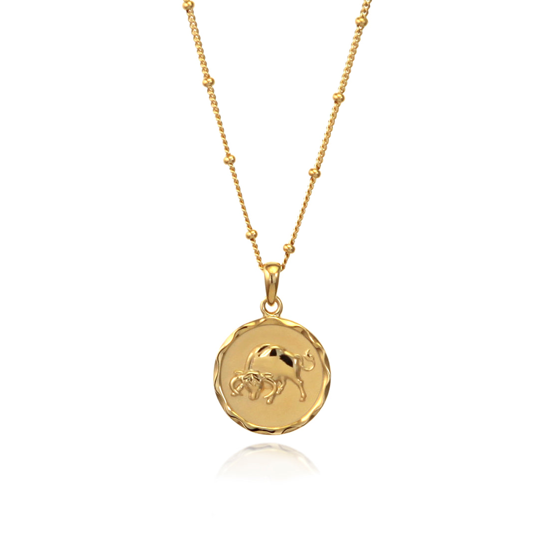 Gold Taurus zodiac star sign necklace with beaded chain on a white background