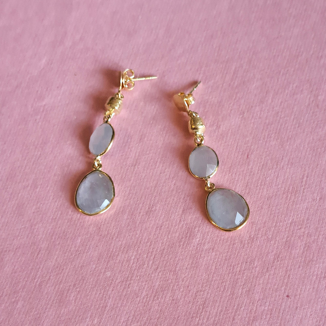 Natural aquamarine drop earrings in gold vermeil on a pink background.
