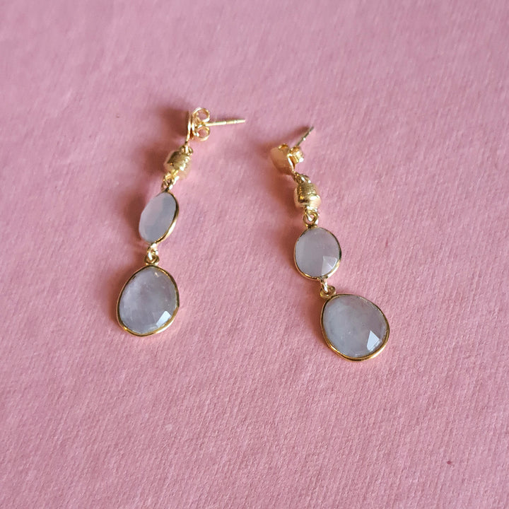 Natural aquamarine drop earrings in gold vermeil on a pink background.