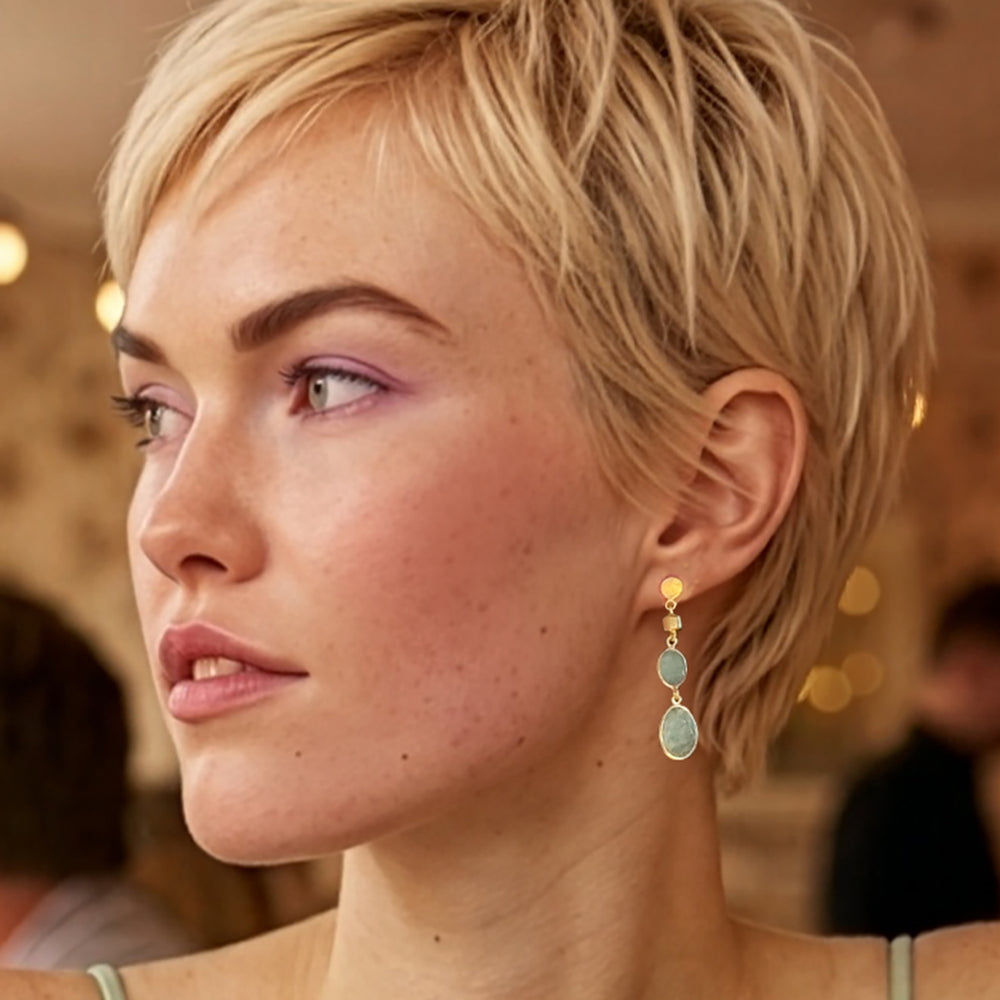 Blond woman wearing aquamarine gemstone drop earrings in gold.