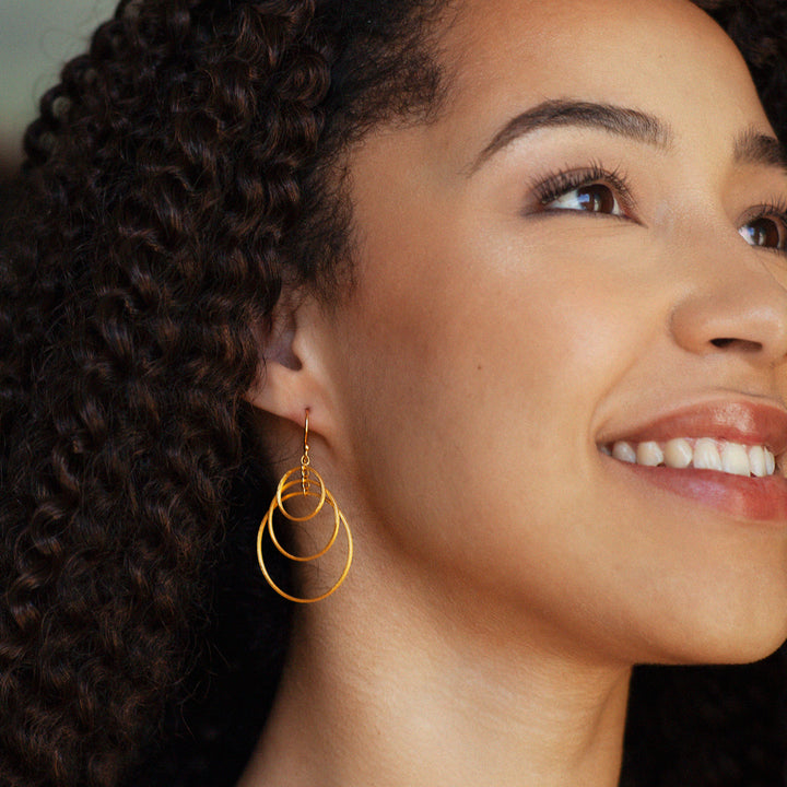 Gold triple hoop drop earrings worn as model shot