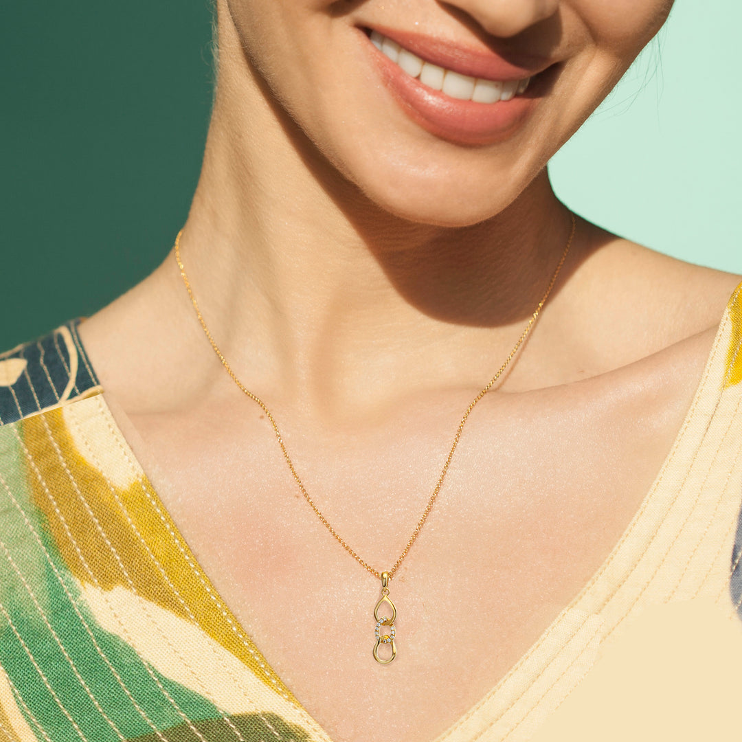 Woman wearing a gold necklace with cubic zirconia pave on a green and blue background