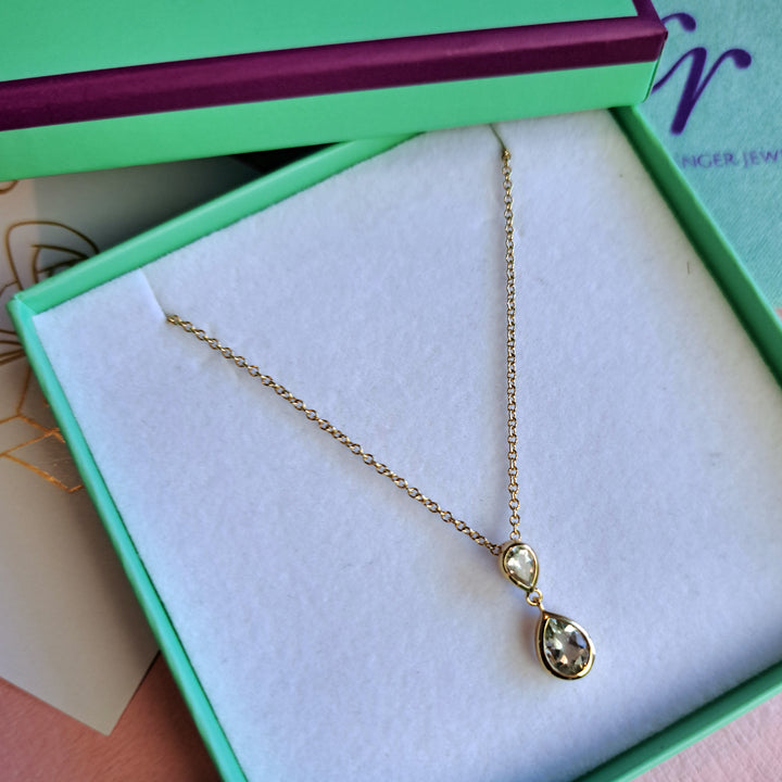 Close-up of 14ct gold two stone drop pendant necklace in green amethyst in a Christin Ranger Jewellery gift box.