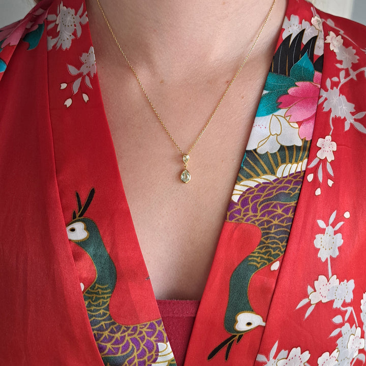 Woman weaering a 14ct gold two stone drop pendant necklace in green amethyst