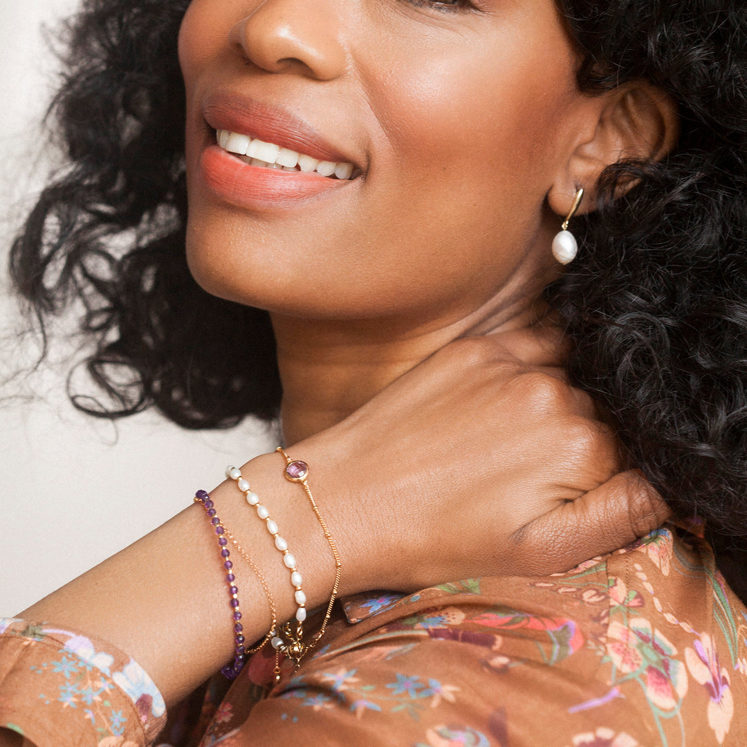 Model wearing  gold amethyst beaded bracelets.