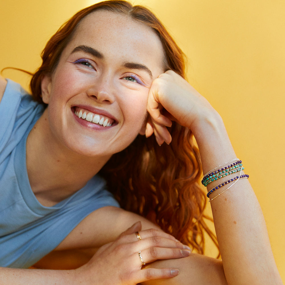 Model wearing gold vermeil lapis lazuli and turquoise gemstone bracelets.