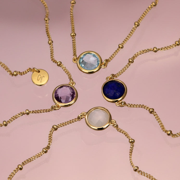 Gold vermeil beaded chain bracelets with lapis lazuli, moonstone, amethyst and blue topaz on a reflective background