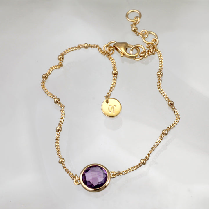 Gold vermeil beaded chain bracelet with amethyst on a reflective background