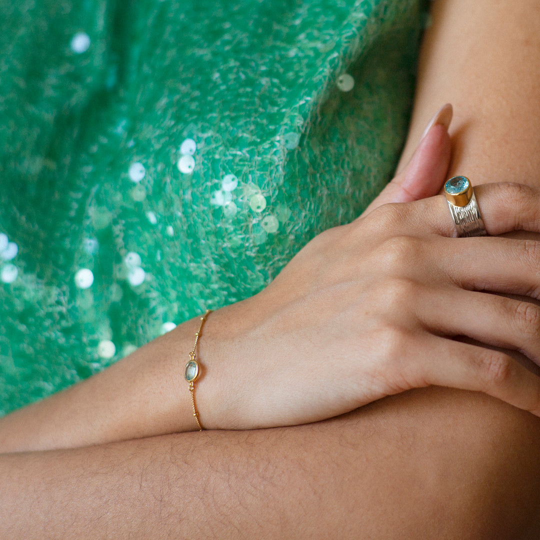 Woman wearing a gold vermeil beaded chain bracelet with blue topaz