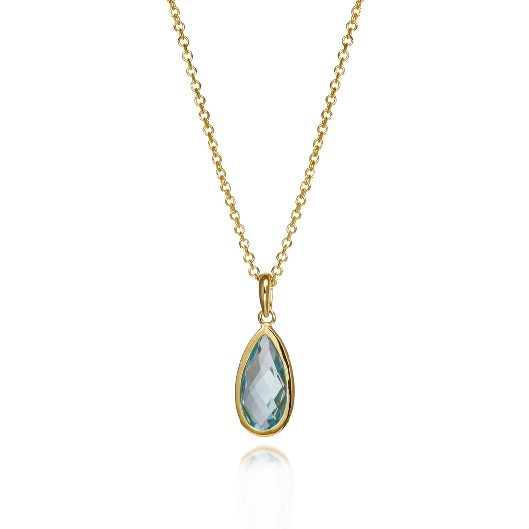 Gold necklace with a teardrop-shaped blue topaz gemstone pendant on a white background