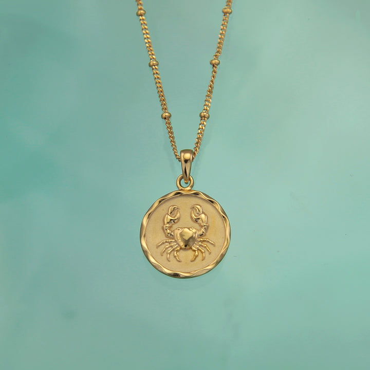 18ct gold vermeil cancer zodiac star sign pendant necklace on a teal background