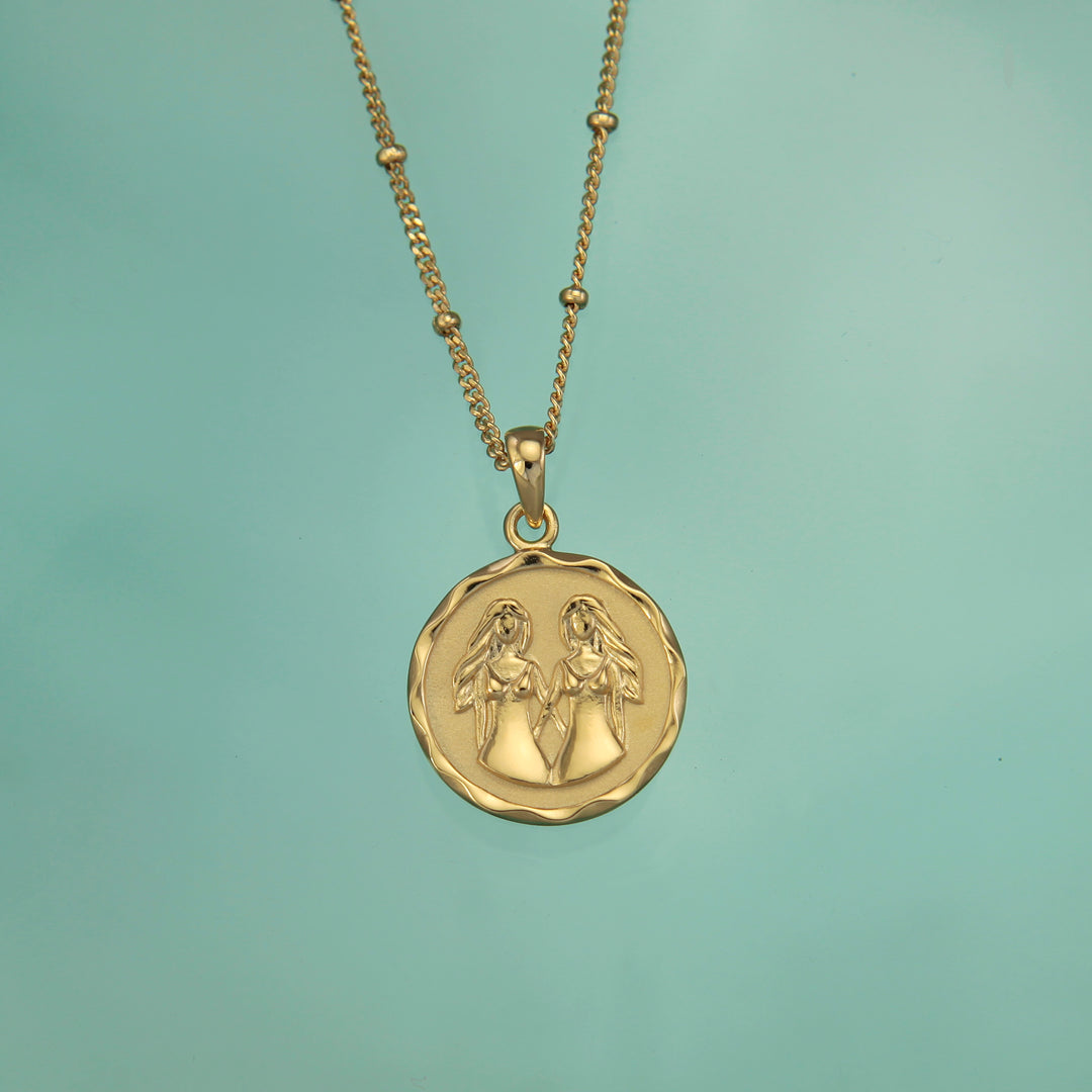 18t gold vermeil Gemini zodiac star sign pendant necklace on a teal background