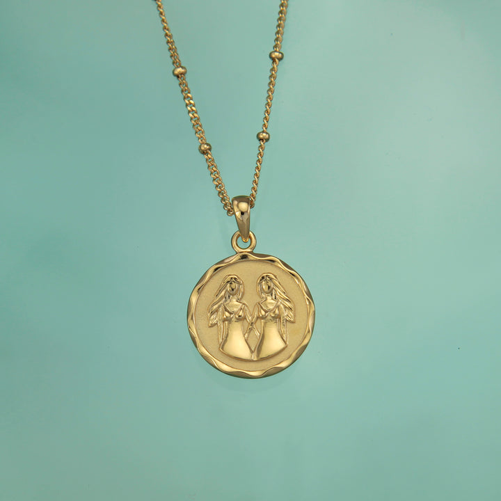 18t gold vermeil Gemini zodiac star sign pendant necklace on a teal background