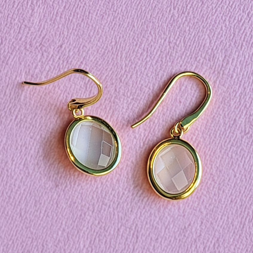 18ct gold vermeil oval drop earrings with white moonstone on an alternative pink background