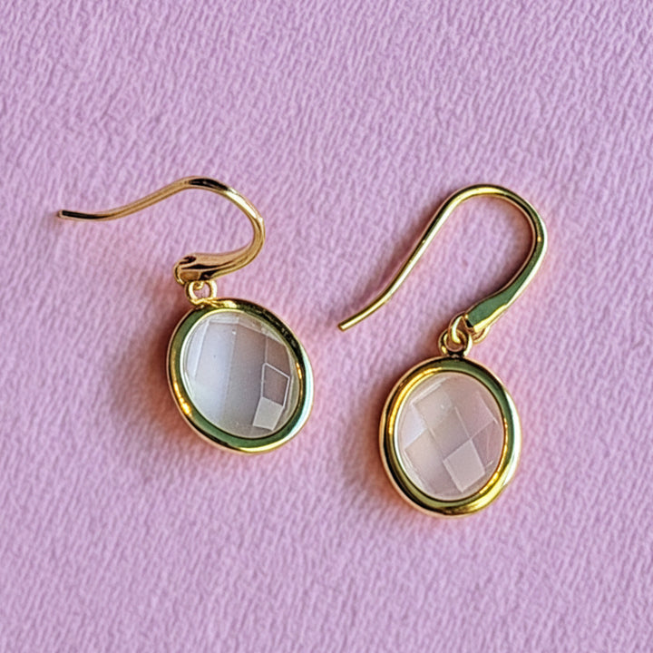 18ct gold vermeil oval drop earrings with white moonstone on an alternative pink background
