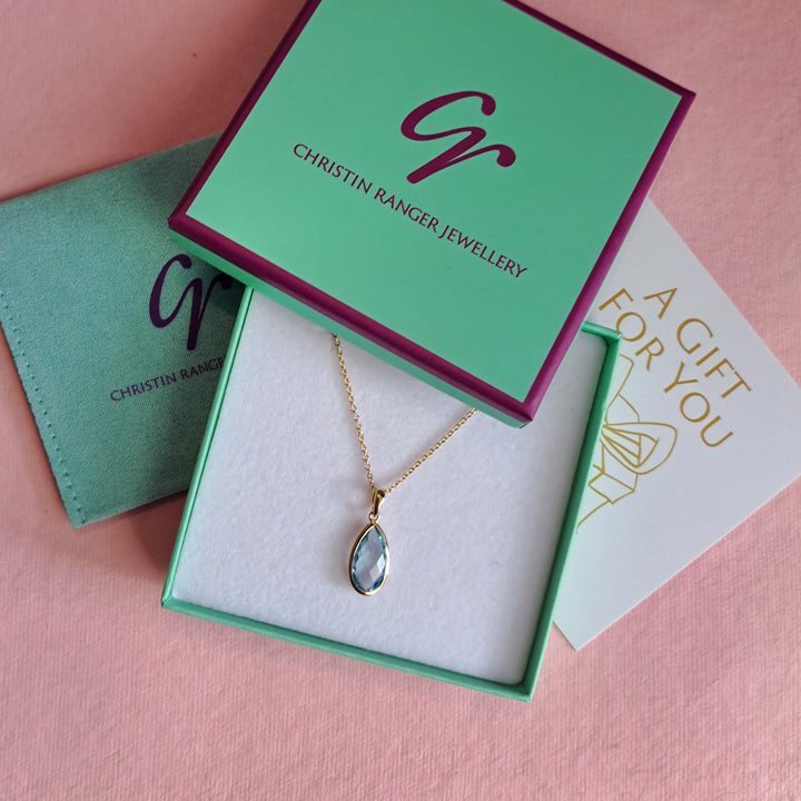 Gold pear drop pendant necklace with blue topaz in Christin Ranger Jewellery  gift packaging