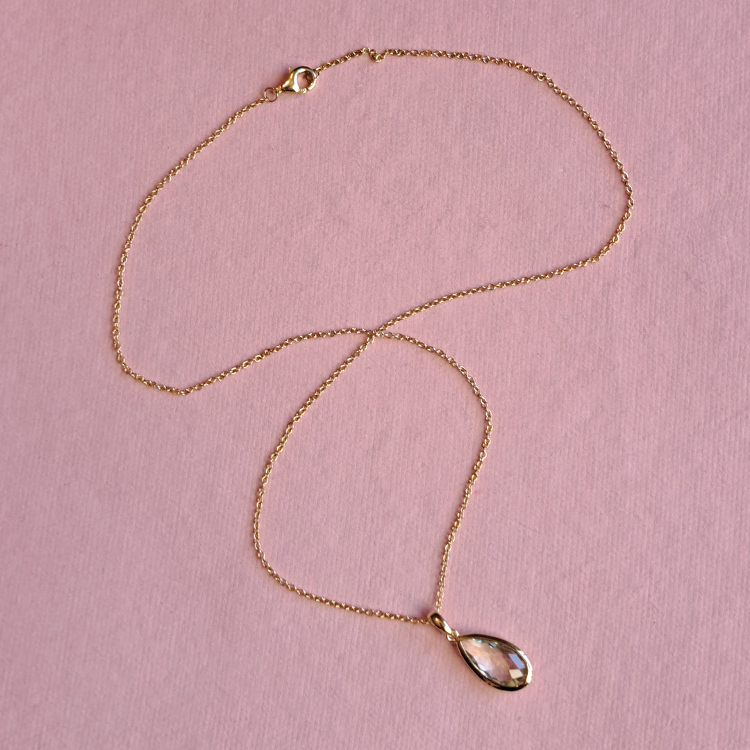 Gold-vermeil-pear-drop-pendant-necklace-green-amethyston a pink background