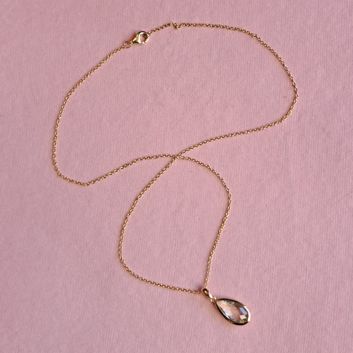 Gold-vermeil-pear-drop-pendant-necklace-green-amethyston a pink background