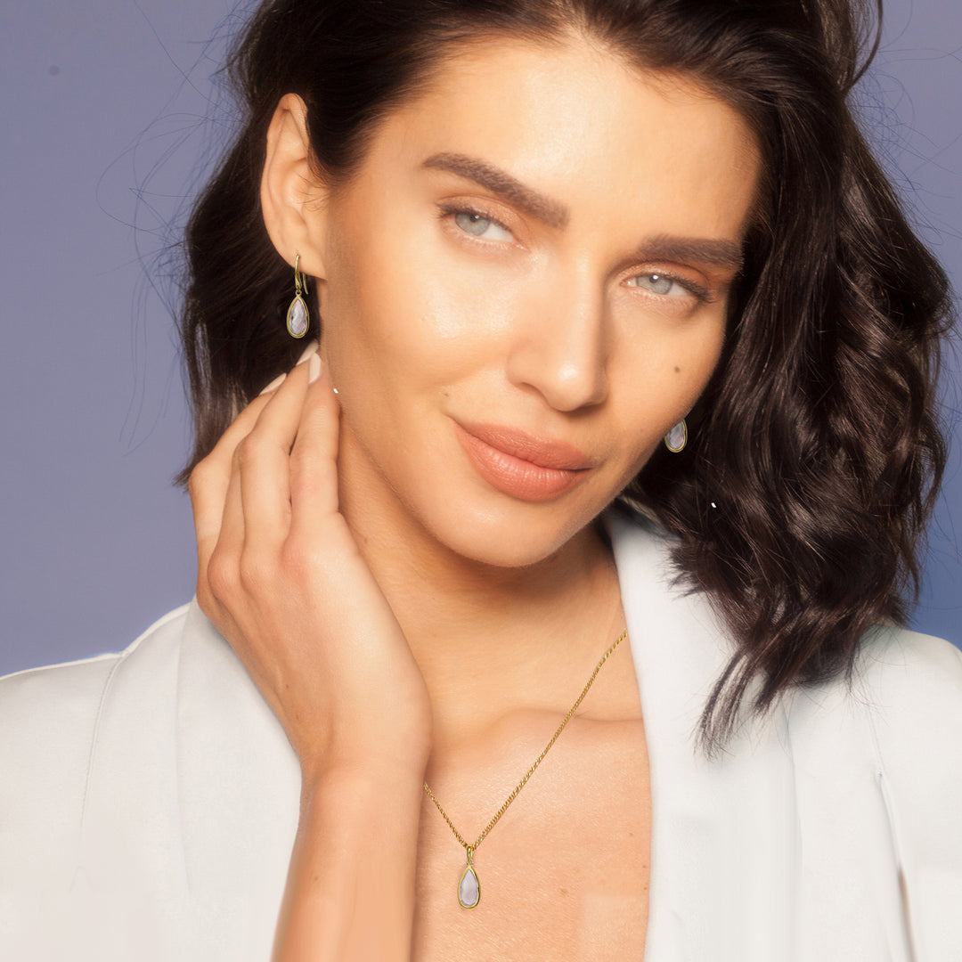 Woman wearing 18ct gold vermeil pear drop earrings and matching necklace set in rose quartz