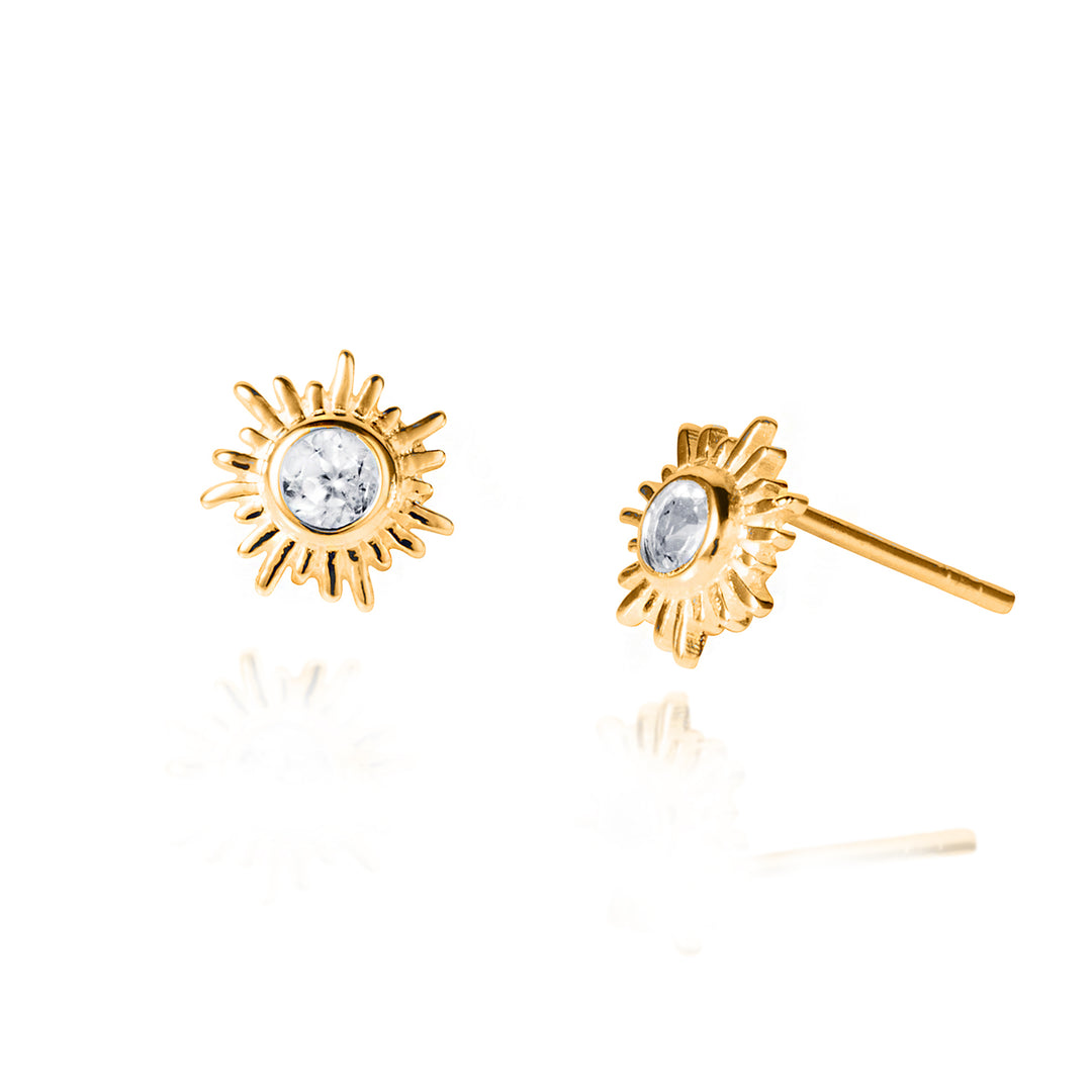 Gold sun-shaped earrings with clear gemstones on a white background