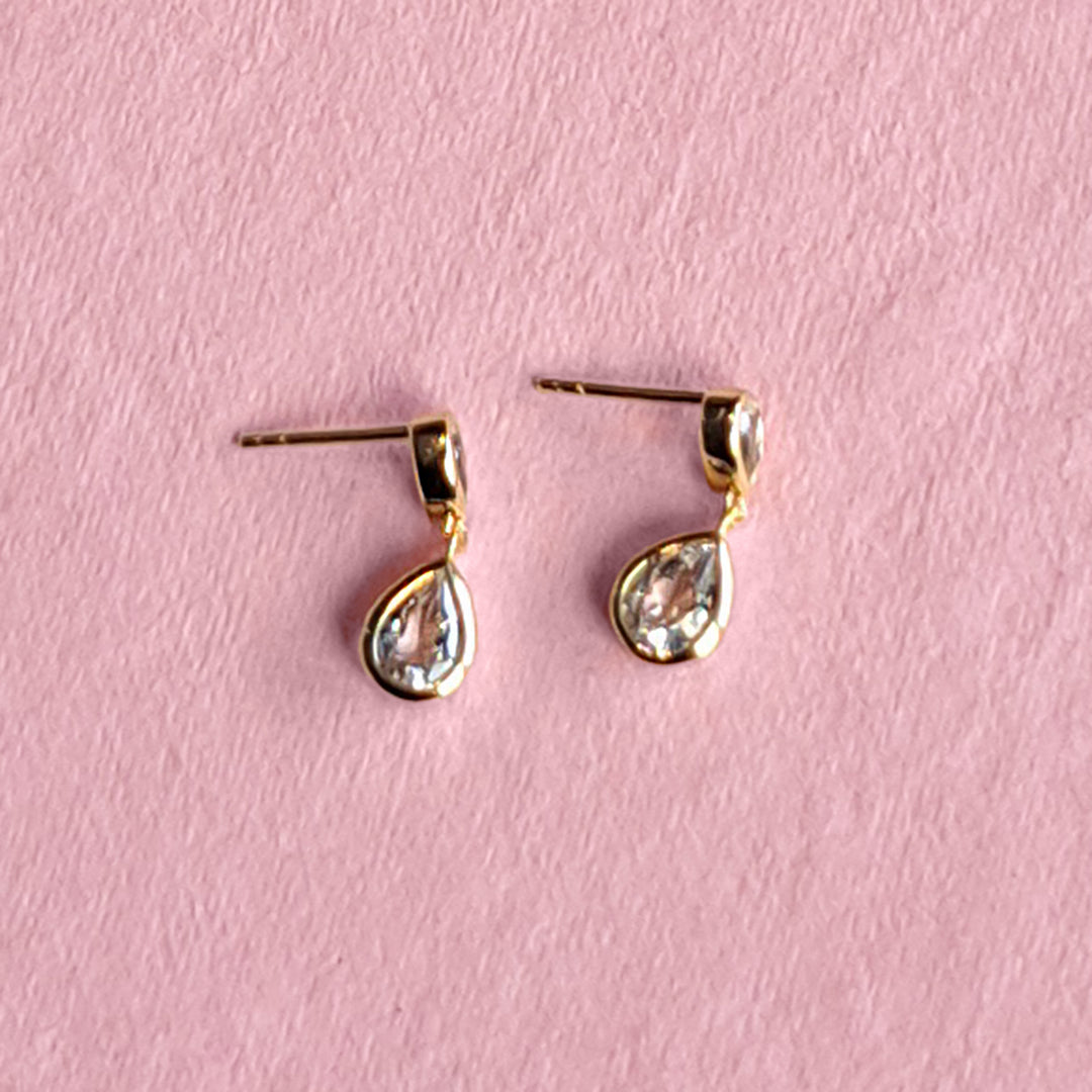 14ct gold vermeil two stone stud earrings with white topaz on a pink background
