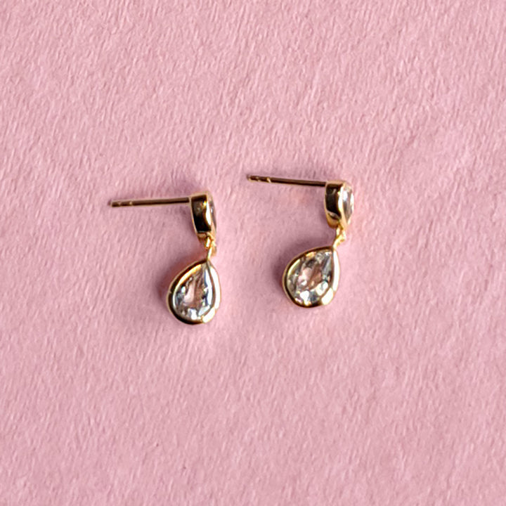 14ct gold vermeil two stone stud earrings with white topaz on a pink background
