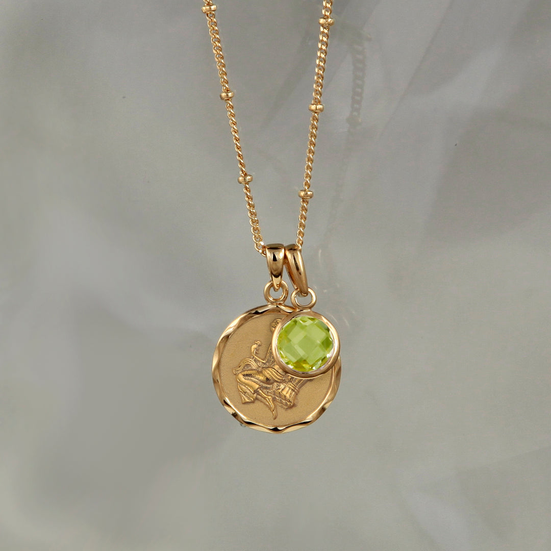 Gold Virgo star sign pendant with a peridot August birthstone charm on a gray background