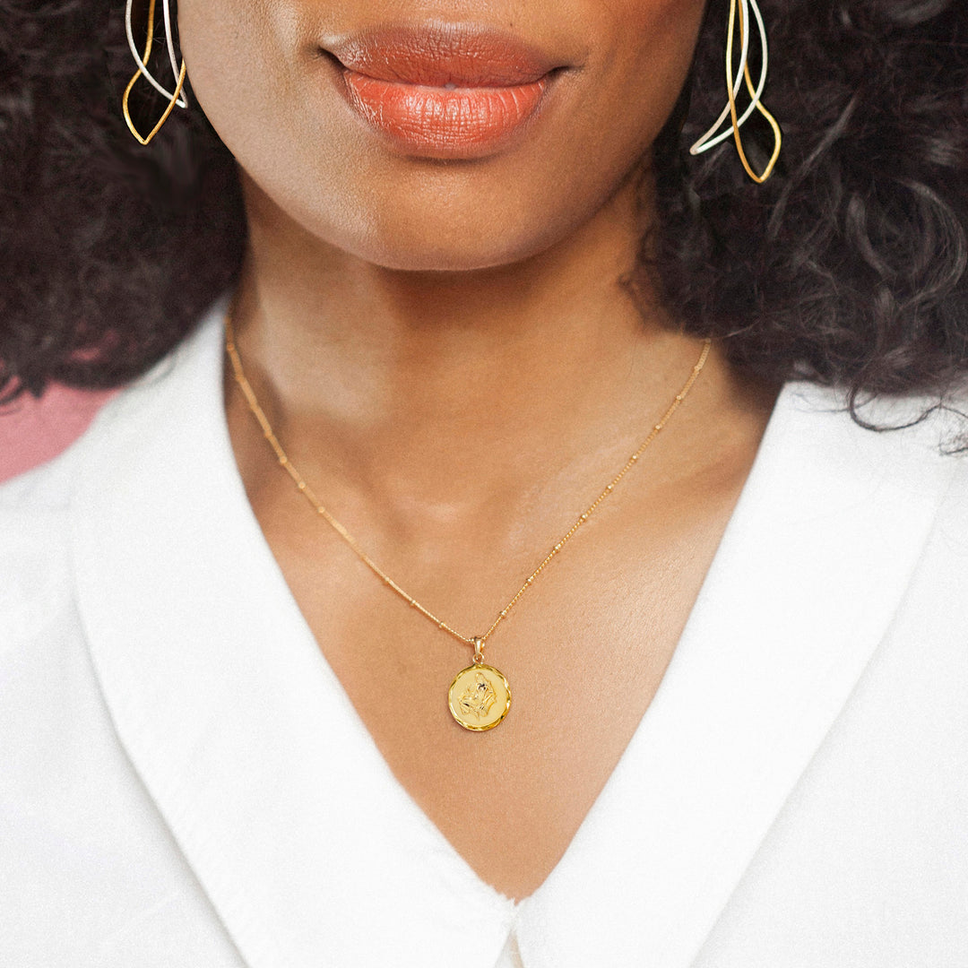 Model wearing a gold Virgo zodiac necklace and white blouse