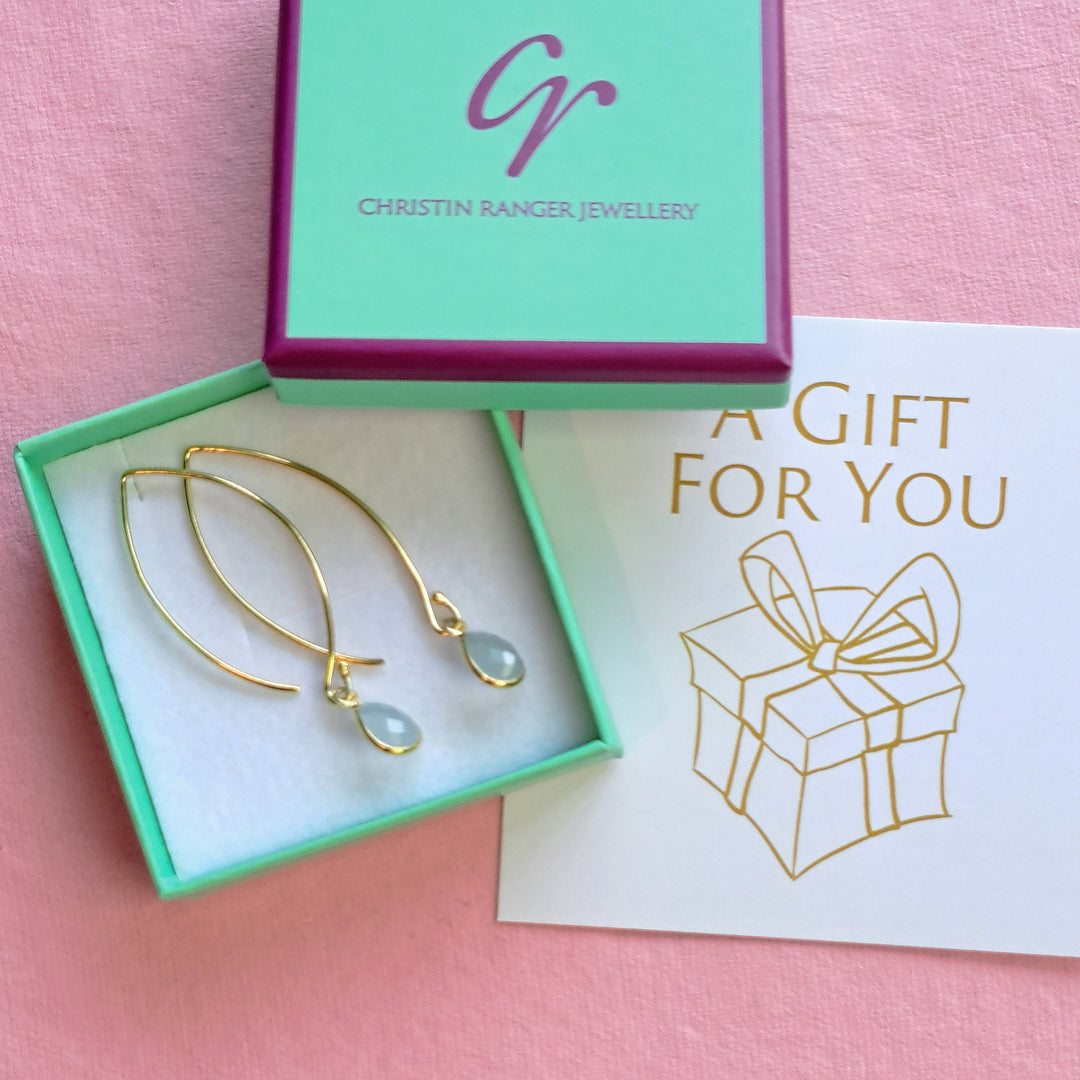 Gold drop earrings with aqua blue gemstones in Christin Ranger Jewellery gift packaging.