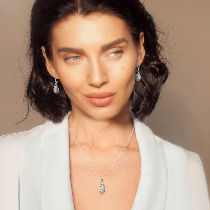 Model wearing a silver teardrop earring and necklace set with green amethyst gemstones 