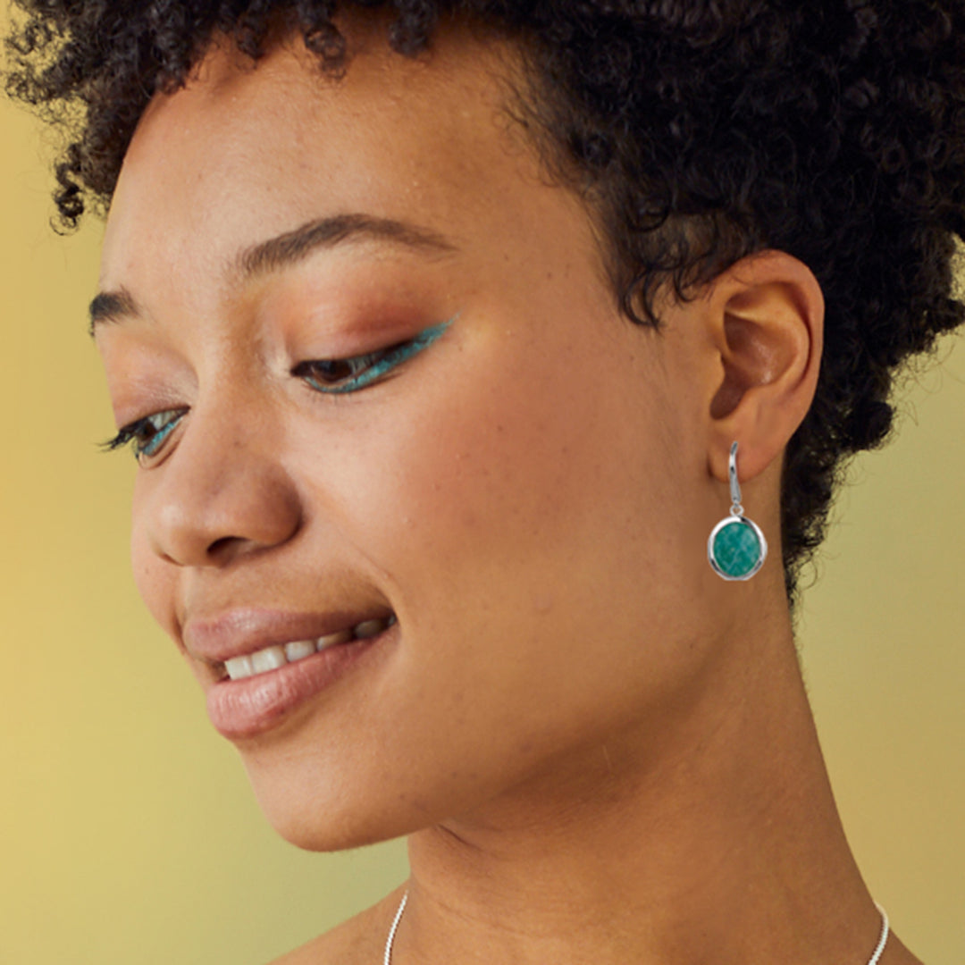 Close-up of a woman wearing amazonite turquoise earrings against a yellow background
