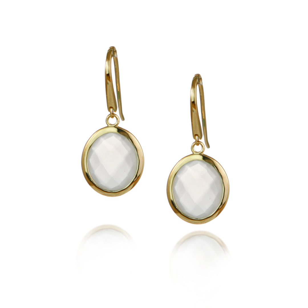 Gold moonstone drop earrings with white stones on a white background