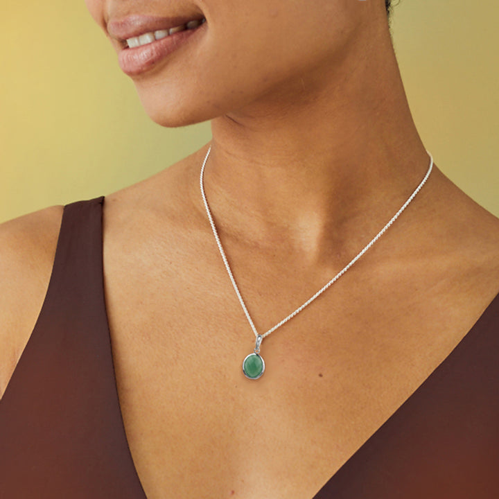 Woman wearing a silver aventurine necklace with a green gemstone against a yellow background
