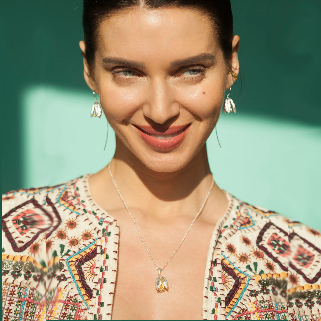Woman wearing a silver floral earring and necklace set on a green background