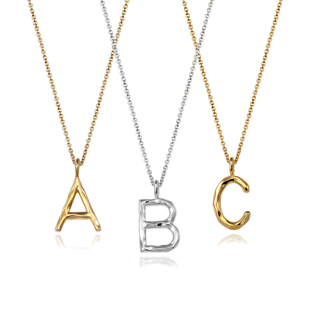Sterling silver and gold vermeil letter initial necklaces against a white background