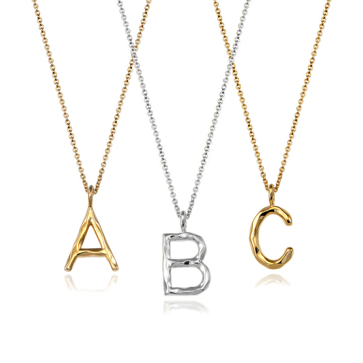 Sterling silver and gold vermeil letter initial necklaces against a white background