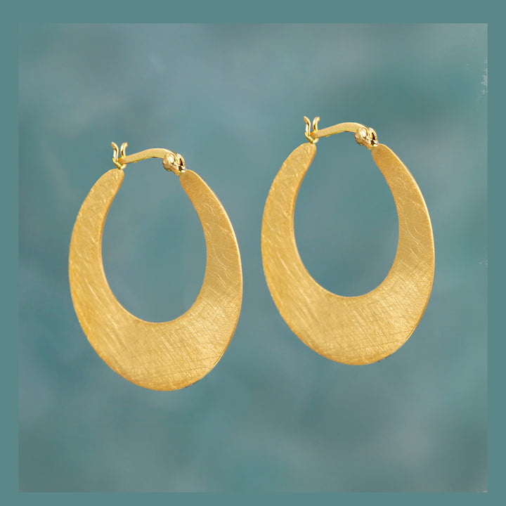 Gold hoop earrings on a textured gray background