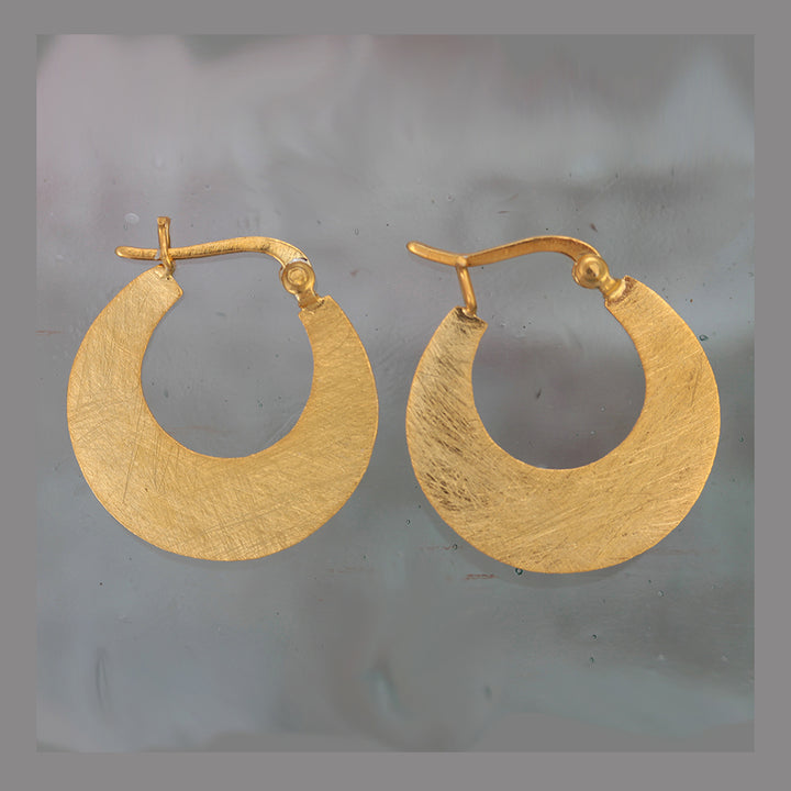 Gold hoop earrings on a gray background