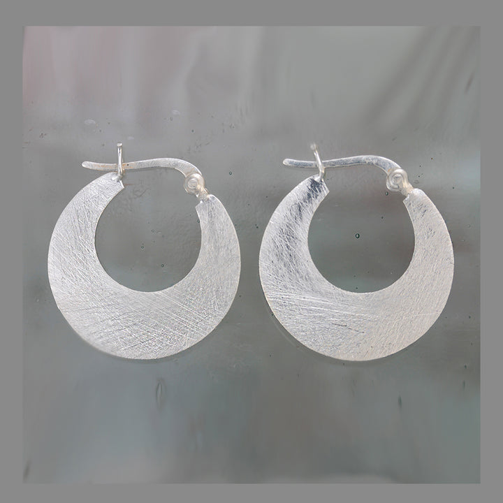 Silver hoop snap-post earrings on a gray background