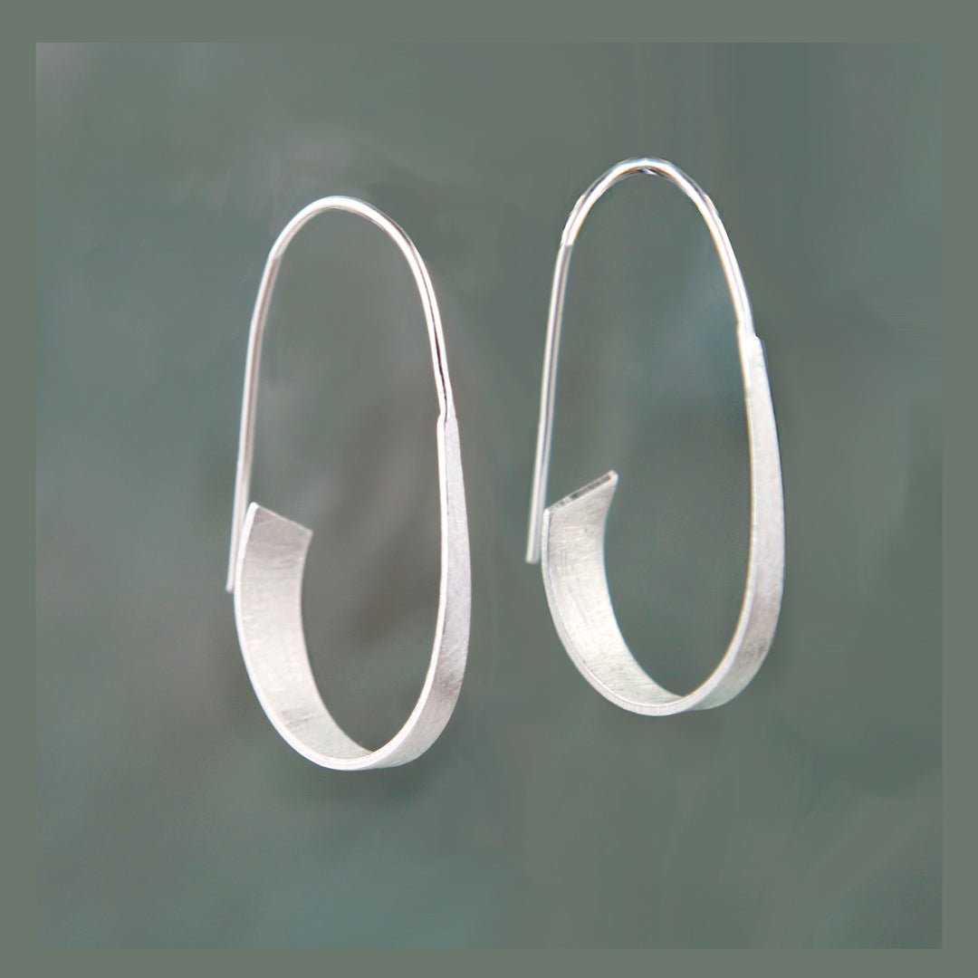 Pair of silver threader hoop earrings on a dark gray background