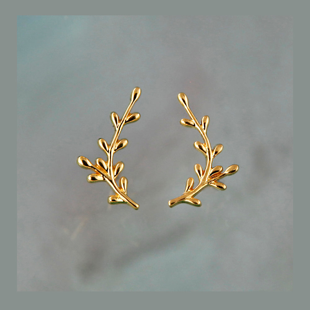Pair of gold branch-shaped earrings on a light gray background